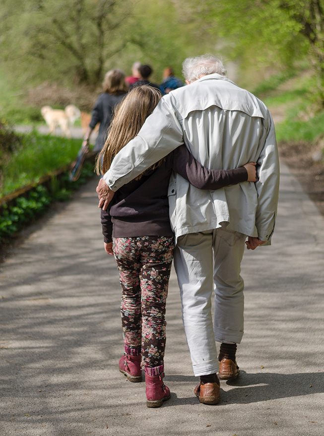 Une jeune fille se promène bras-dessus bras-dessous avec un senior.